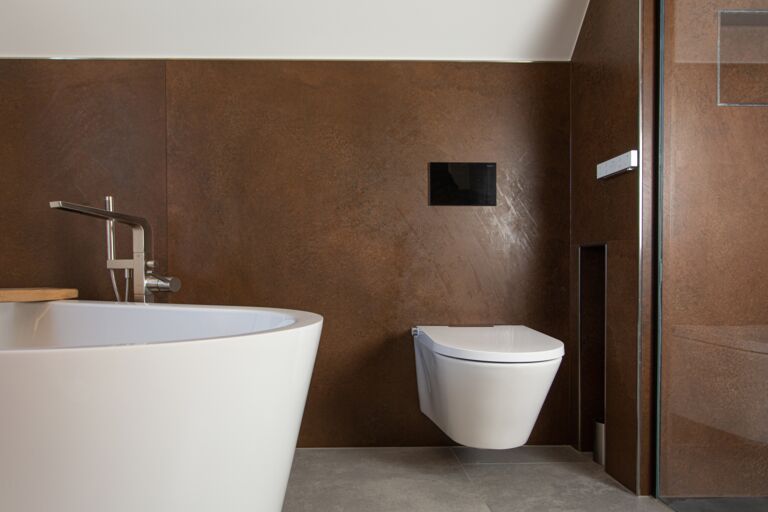 Modernes weißes Dusch-WC installiert an Rückwand in brauner Steinoptik