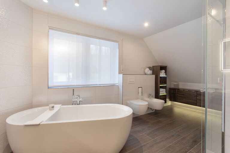 Blick auf hochmodernes saniertes Bad mit freistehender Badewanne, Bidet und luxuriösen Holzinterieur