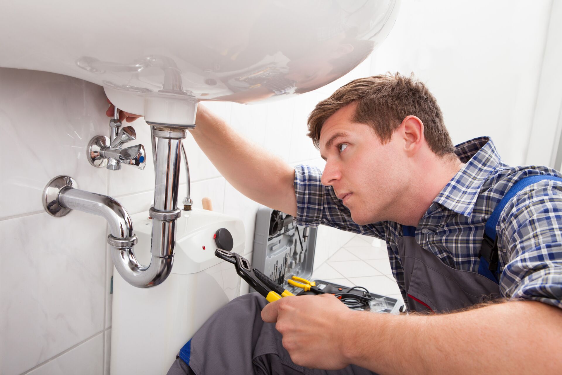 Symbolfoto: Anlagenmechaniker im Sanitär-, Heizungs- und Klimahandwerk repariert Waschbecken