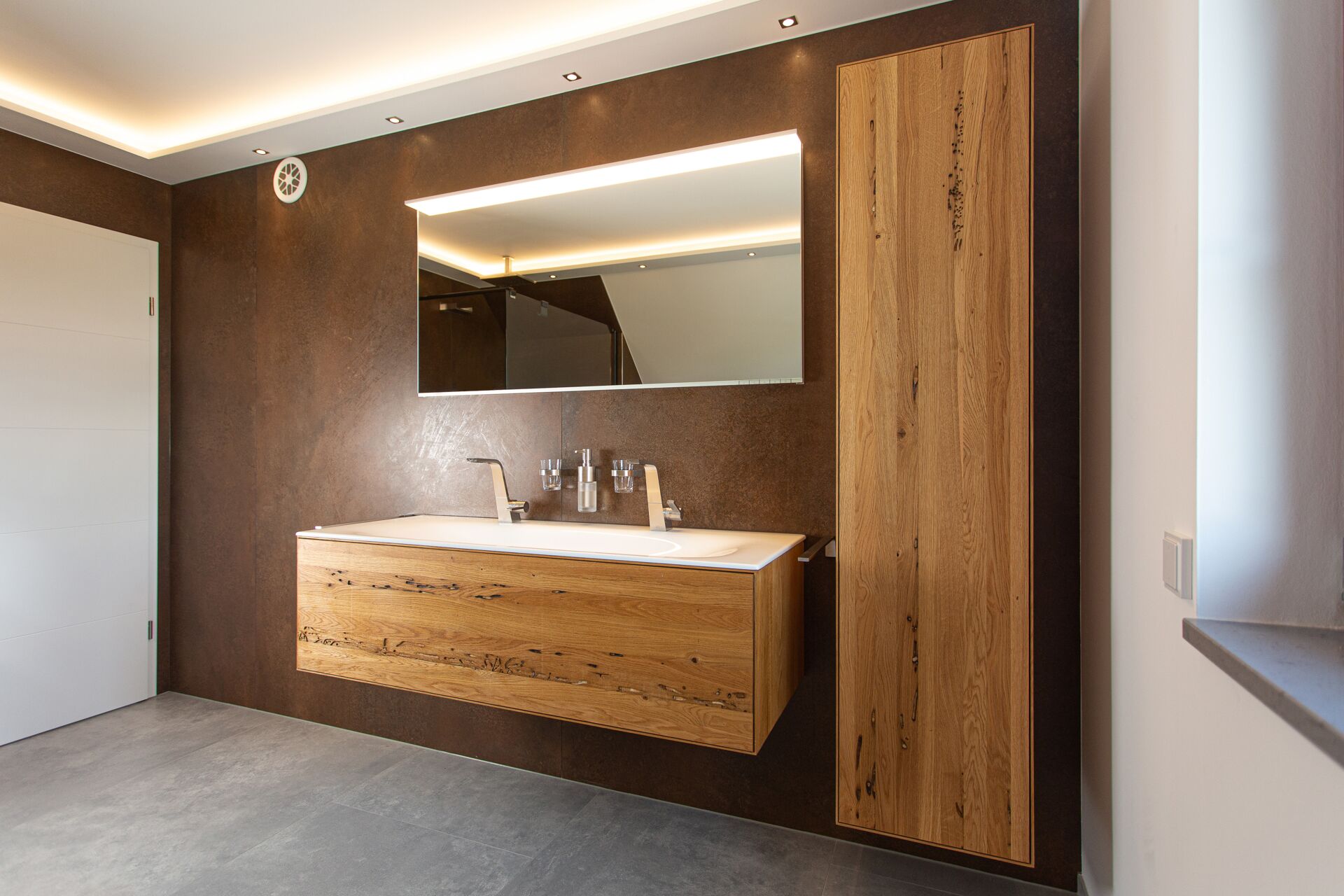 Blick auf hochwertige Waschtischmöbel-Anlage aus Massivholz mit beleuchtetem Spiegel
