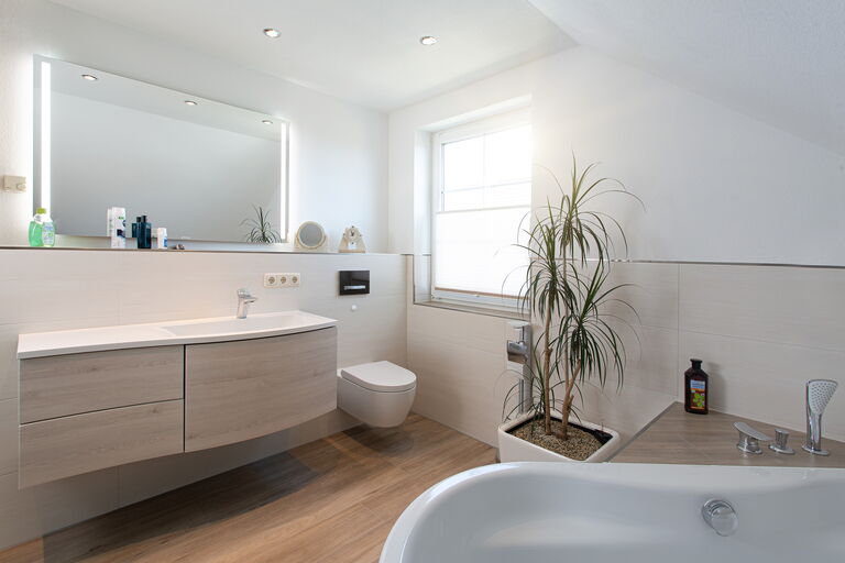 Ein zeitloses Bad mit ausgefallener Badewannen-Anlage, Dusch-Anlage mit beleuchteter Rückwand als „Hingucker” und erneuerter Waschtisch- und WC-Anlage.