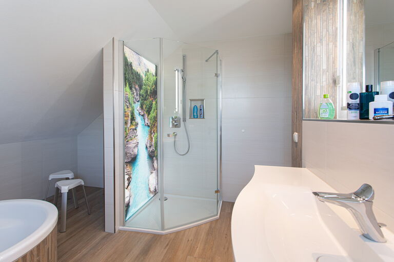 Blick auf eine moderne Dusch-Anlage mit beleuchteter Rückwand mit Wasserfall-Motiv